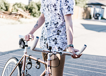 An unidentifiable person standing next to a bike. Their head is not in the frame.