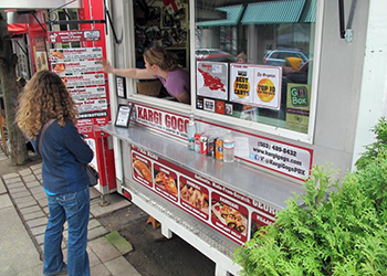 A woman ordering at a food cart.