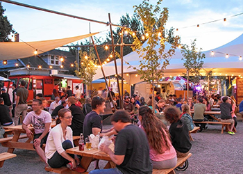 A large crowd of patrons at a food cart pod.